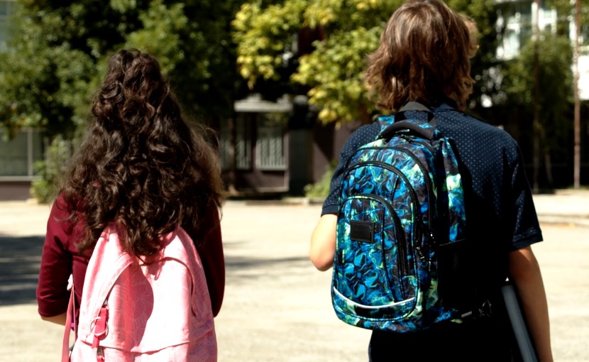 Two students walking with backpacks on their back
