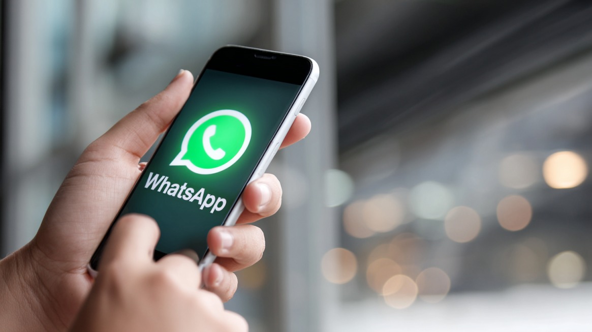 Person holding smartphone with WhatsApp logo on screen