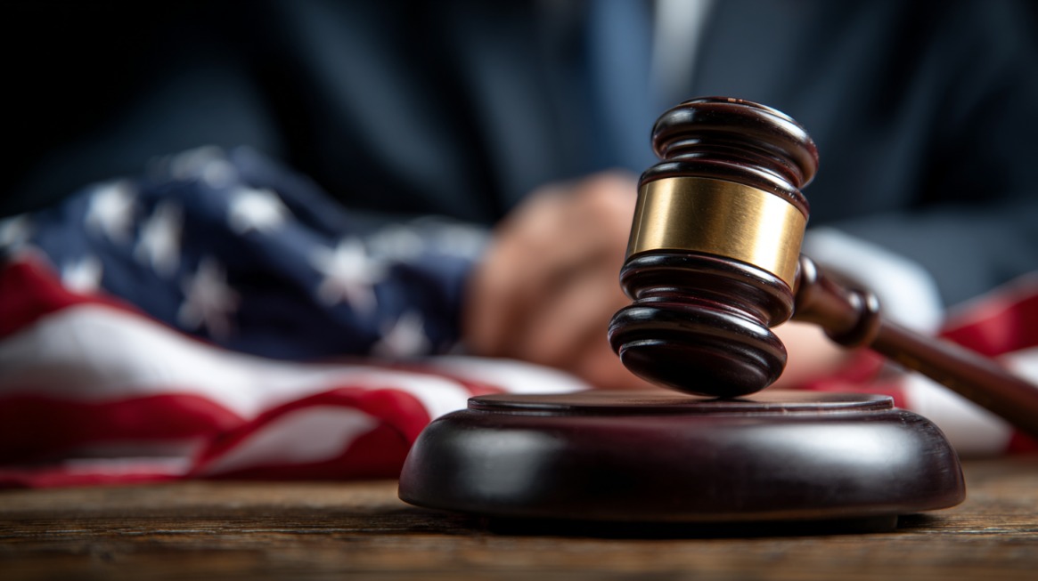 Judge’s gavel on a wooden desk with the American flag blurred in the background, symbolizing the U.S. trial and enforcement process in international lawsuits