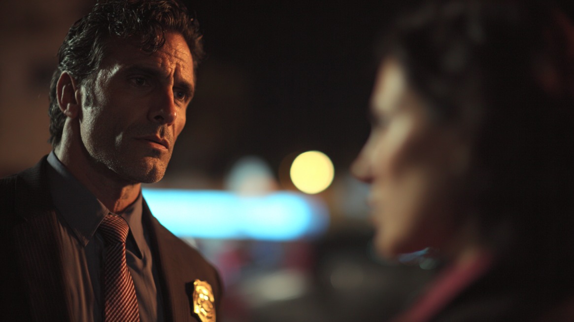 A serious-looking officer speaking to a person at night, symbolizing the concept of reasonable suspicion in searches