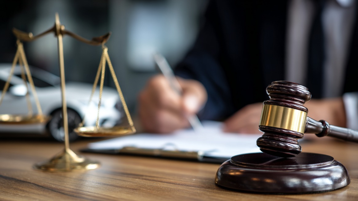 Close-up of a judge writing with a gavel and scales of justice on the desk, symbolizing legal and constitutional debates around polygamy laws in the U.S.