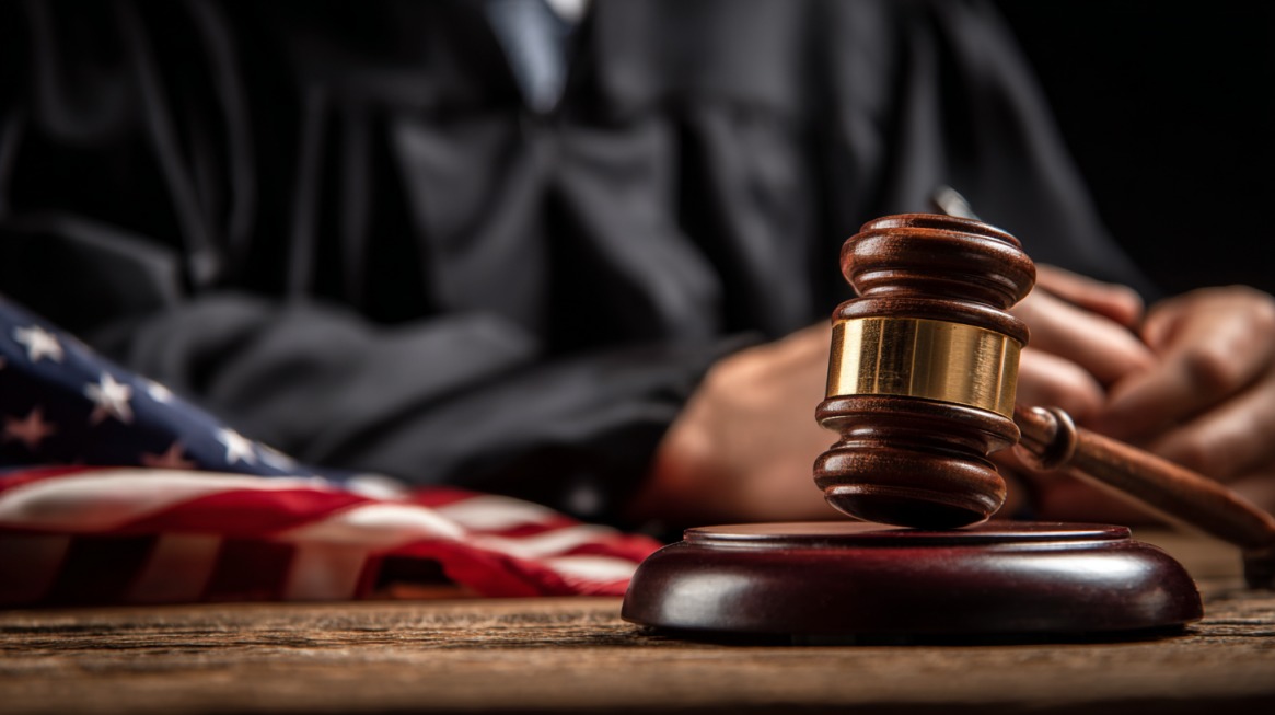 Judge’s gavel on a wooden desk with the American flag in the background