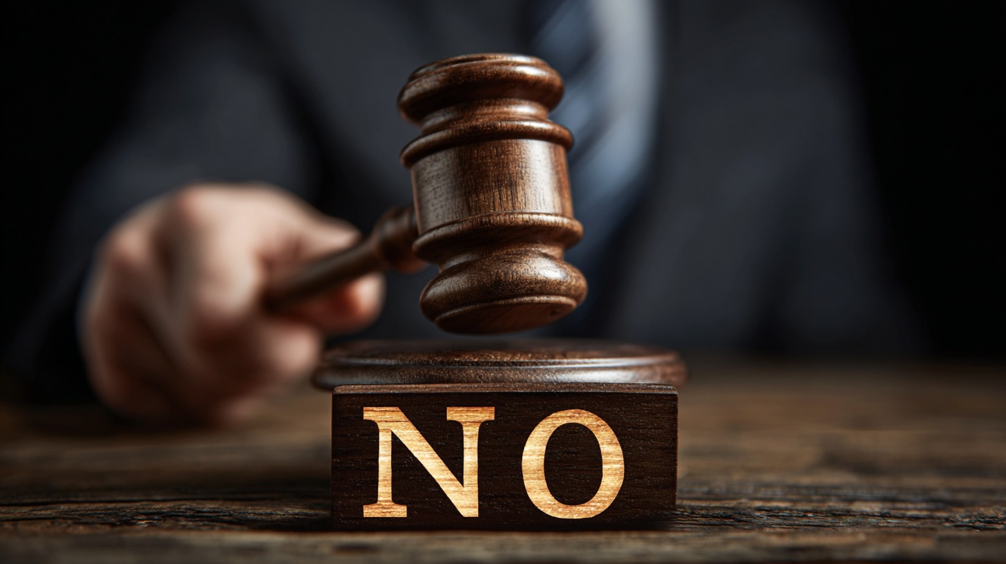 Close-up of a judge’s gavel striking near a wooden block engraved with the word “NO,” symbolizing a no contest plea in court.