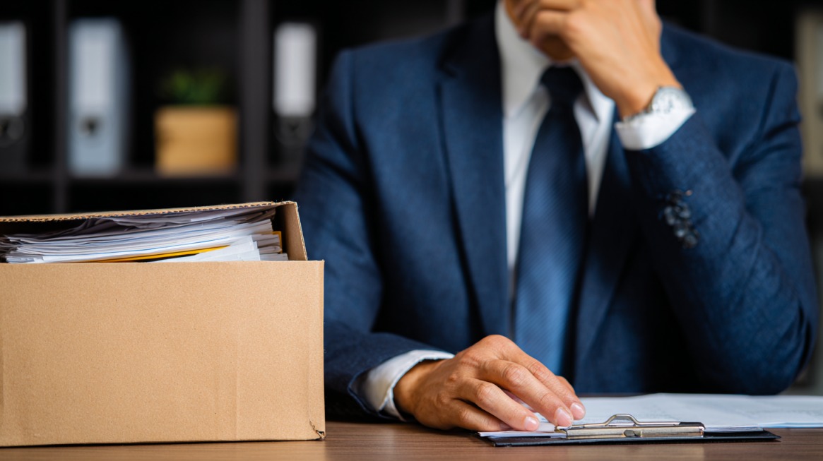 Man in a suit with a box of files on desk, representing legal work and mixed fee arrangements
