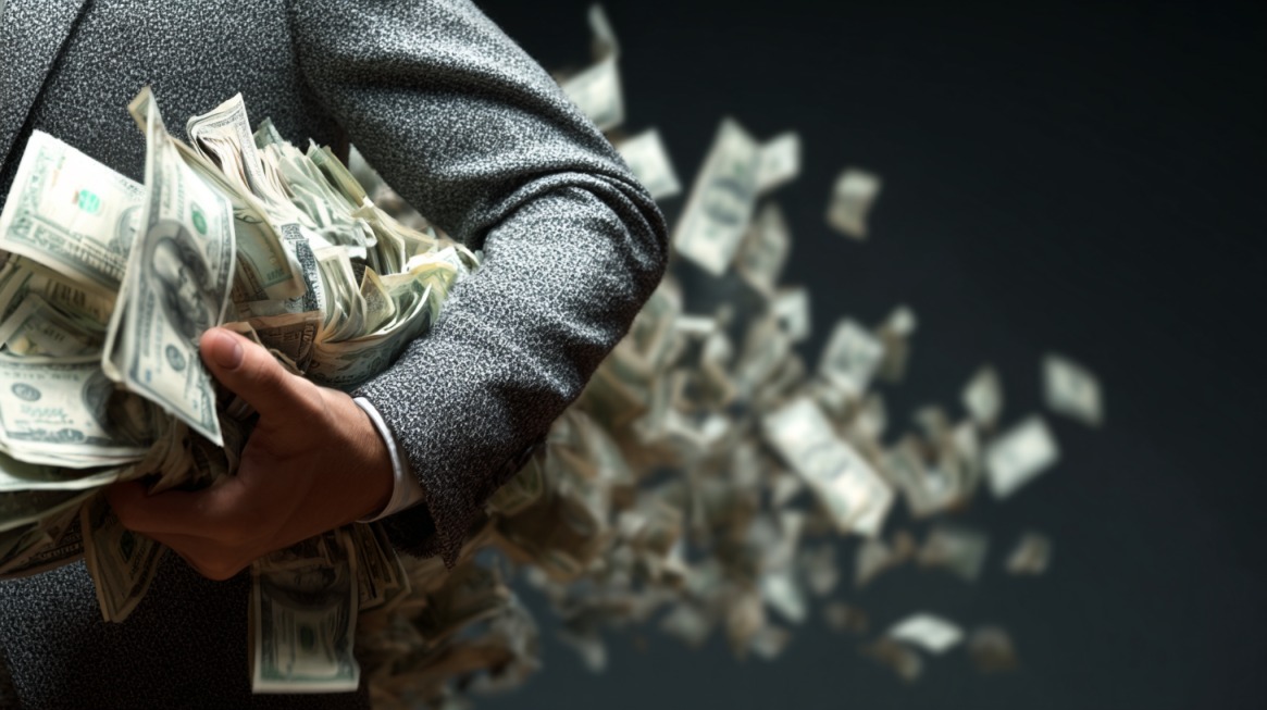 Person holding stacks of money with cash spilling out in the background