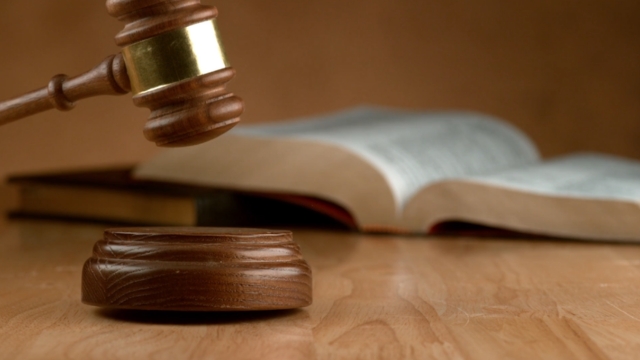 A judge’s gavel rests near an open law book, symbolizing enforcement and compliance under the HIRE Act