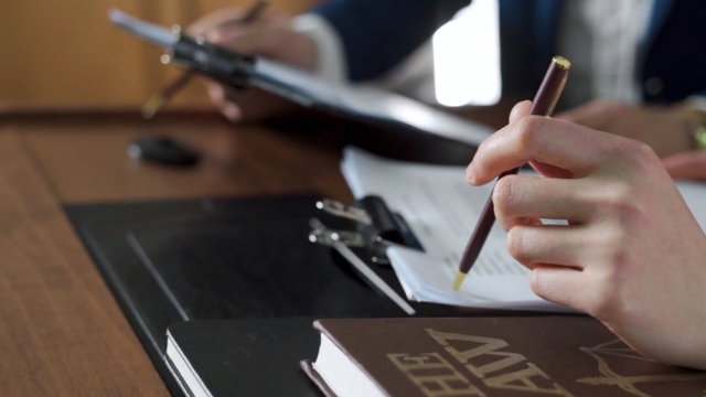 Two professionals review legal documents with a law book on the desk, highlighting Executive Order 14173 for federal contractors
