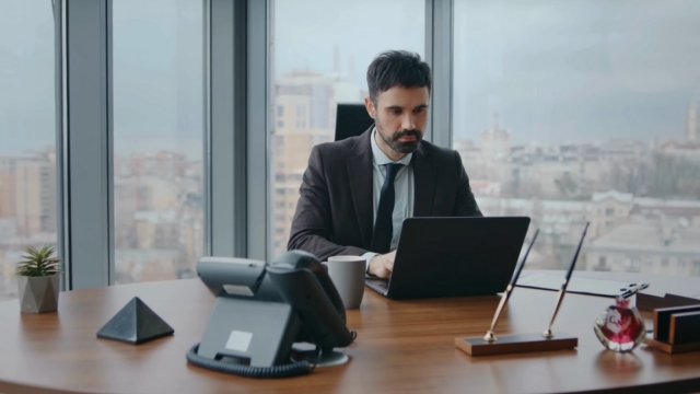 A businessman prepares documents on his laptop for H-1B visa petition filing