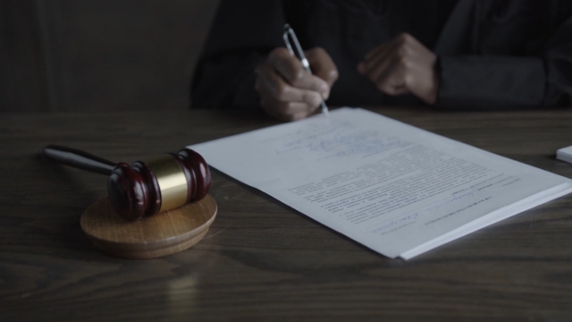 A judge signs legal documents beside a gavel, representing the key provisions of Executive Order 14173