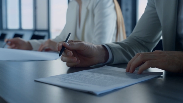 Two people review and sign documents, reflecting new opportunities for workers under the HIRE Act