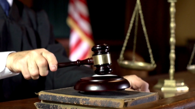 A judge strikes the gavel in a courtroom with scales of justice in the background, symbolizing the court’s decision to block the FLSA overtime rule