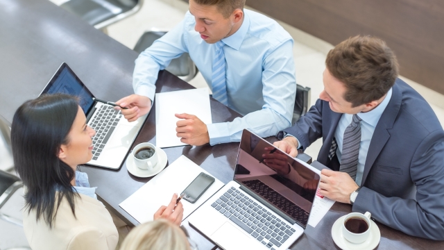 Colleagues meet with laptops to discuss worker classification rules under Executive Order 14173