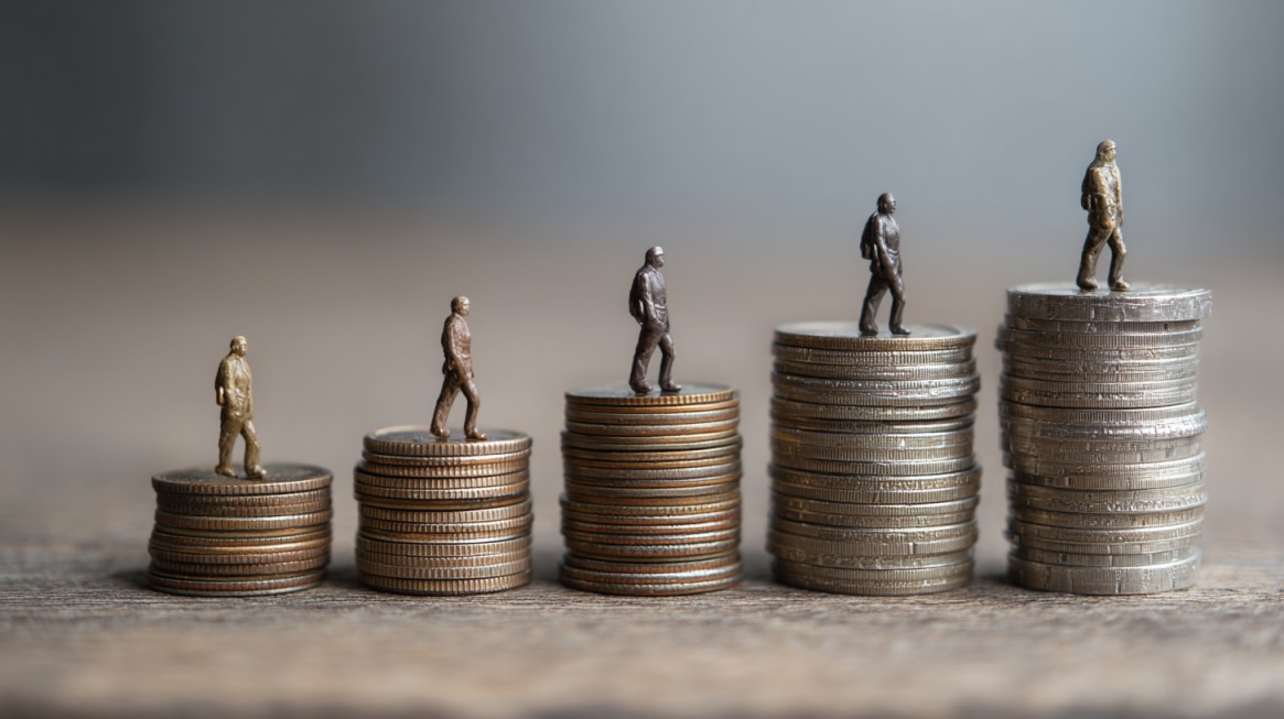 Miniature figures standing on increasing stacks of coins