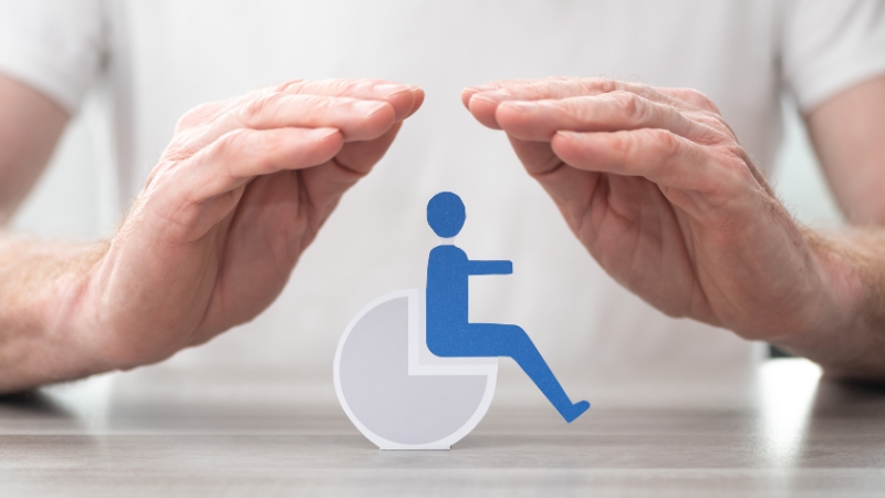 Hands form a protective gesture around a wheelchair symbol, representing legal protections for people with disabilities under federal law