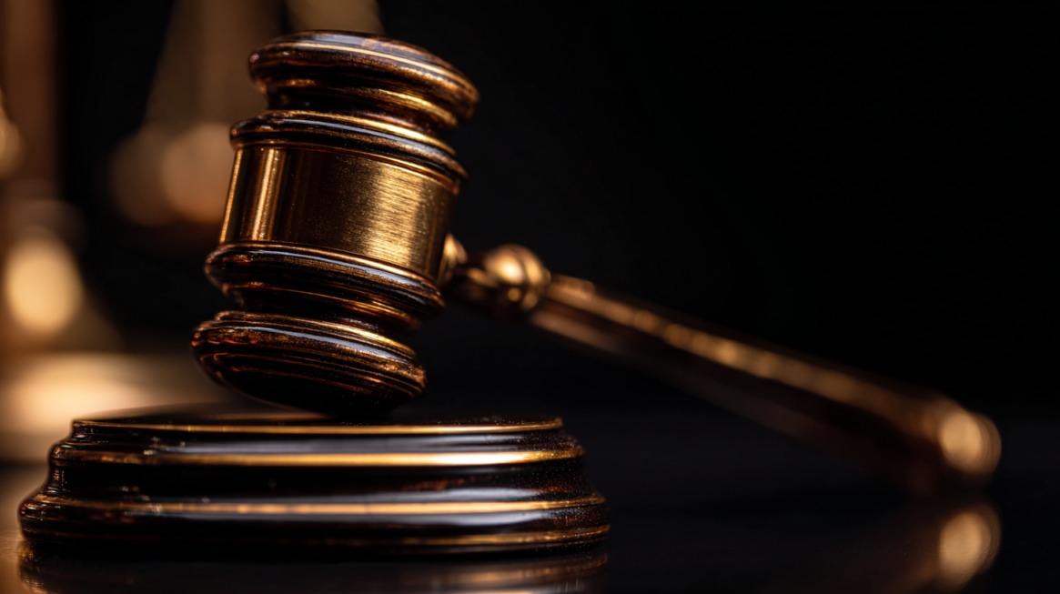 Close up of a judge’s gavel resting on a sound block in a dark courtroom
